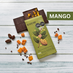 Kuyay dunkle Schokolade mit Mango in grüner Verpackung, umgeben von Mangostücken, Kakaobohnen und Nibs – hochwertige 70 %-Schokolade mit fruchtiger Note